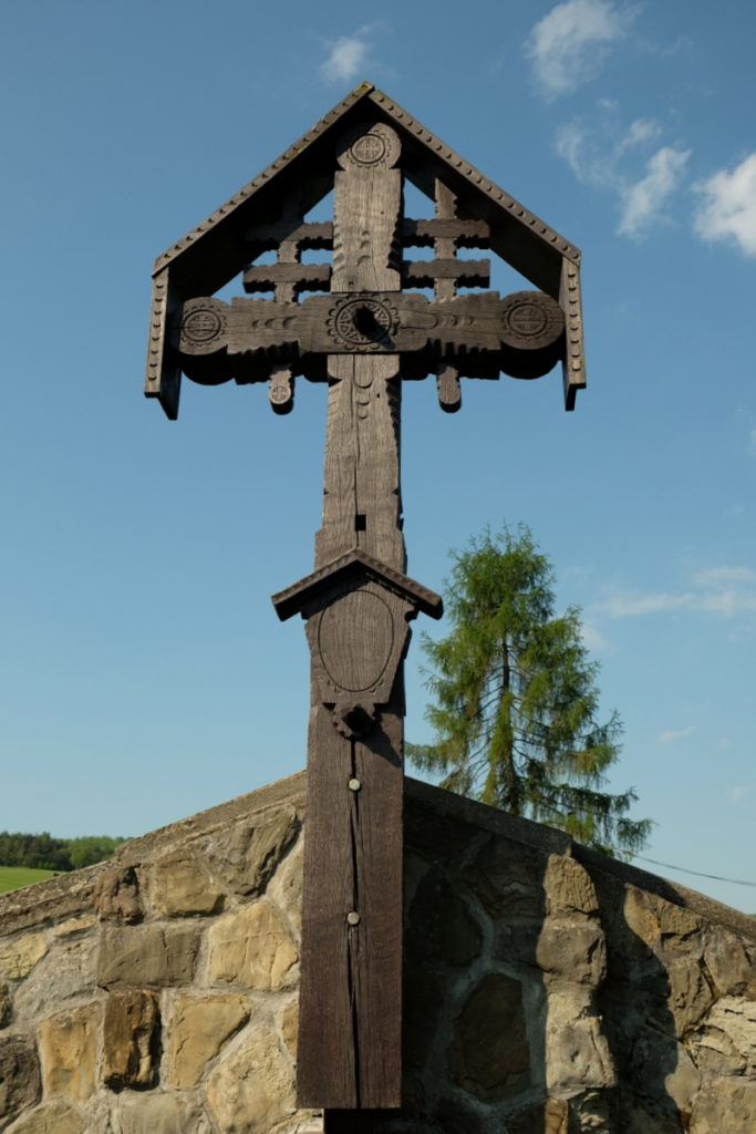 Oryginalny drewniany krzyż wieńczący kamienny mur